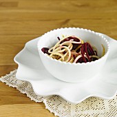 Vegetable spaghetti made from beetroot and yellow courgettes in a white bowl
