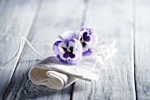 White linen napkin and violas on wooden surface