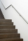 Treppenaufgang aus dunkelgrauem, poliertem Beton, an Wand Edelstahl Handlauf