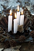 Four candles in a baking tin with a wreath of alderberries and maple fruit