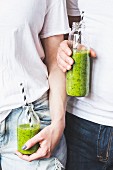 Spinach, mango and banana smoothies in bottles with straws