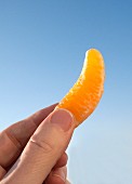 A hand holding a mandarin segment