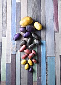 Various types of potatoes on a colourful wooden surface