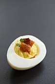 A devilled egg with bacon