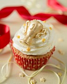 A cupcake decorated with vanilla butter cream and a golden trophy