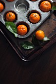 Clementines in a muffin tin and on a baking tray