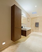 Floating cupboard and washstand with wooden fronts in designer bathroom painted beige