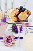 A spiral cake with blueberries and vanilla sauce on a glass stand