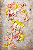 Various different coloured farfalle (natural, turmeric, spinach, beetroot) on a metal surface