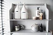 Masculine toiletries, shaving brush and decorative tin on vintage wooden shelves painted pale grey