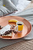 Mug of coffee, banana and toast on tray on bed