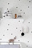 White wallpaper with pattern of black stars and two star-patterned cases on vintage bracket shelf