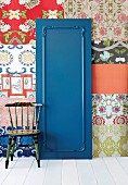 Blue-painted door with decorative moulding against wall covered in patchwork of different wallpapers