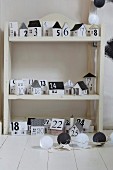 Advent calender made from black and white paper houses on shelves