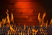 A flaming hot barbecue grill against a wooden wall
