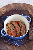 Sausages wrapped in ham with sage and tomatoes