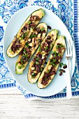 Baked courgettes stuffed with raisins, shallots and red onions