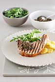 A grilled chop with potato and rocket salad