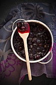 A wooden spoon on top of a pot of blueberry jam