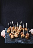 A woman serving meatballs on sticks for a party