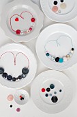 Necklaces made from colourful buttons and coloured cotton cords on plates