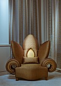 Extravaganter Sessel in Blumenform mit goldfarbenem Bezug vor bodenlangem Vorhang