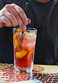 Mann trinkt Cocktail bei einem Imbissstand