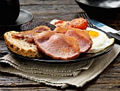 An English breakfast with bacon, fried eggs, tomatoes and black pudding