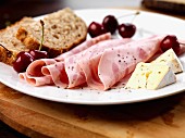 Slices of beer ham, soft cheese, cherries and bread