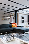 Lounge area with corner sofa, coffee table and view into open-plan kitchen