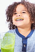 A boy drinking a green smoothie with smeared lips