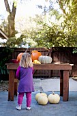 Little girl standing in front of Halloween pumpkins