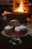 Hazelnut chocolate cake on a cake stand in a room with a fireplace