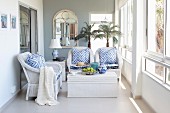 Comfortable wicker furniture, blue and white accessories and two potted palms in bright loggia
