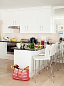 Bar stools at counter in black and white open-plan kitchen