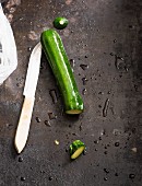 A courgette with a knife on a metal surface