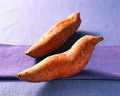 Two sweet potatoes on a purple surface
