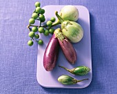 Various types of aubergines on a purple chopping board