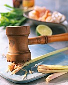 Lemongrass being crushed with a kitchen hammer