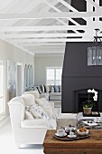 Rustic coffee table, white armchairs and black fireplace in background