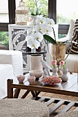 White orchid in gilt trophy and various vases on coffee table