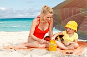 A mother and daughter on a blanket on a beach