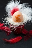 An egg decorated with an Easter stamp in an egg cup with feathers
