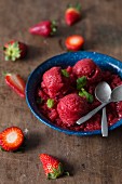 Strawberry sorbet with fresh mint in a rustic blue bowl
