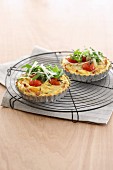 Mini tomato quiches with ham and rocket on a wire rack