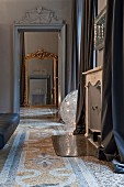 View through door with stucco elements onto antique floor mirror, terrazzo floor
