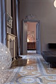 View through coffered door with stucco element onto antique chest of drawers, terrazzo floor