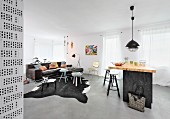 Kitchen counter, side tables on cowhide rug and leather sofa in open-plan interior