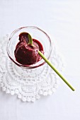 Blackberry and red wine ice cream in a glass bowl with a wooden spoon