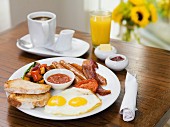 Englisches Frühstück mit Spiegeleiern, Würstchen, Speck & Brot